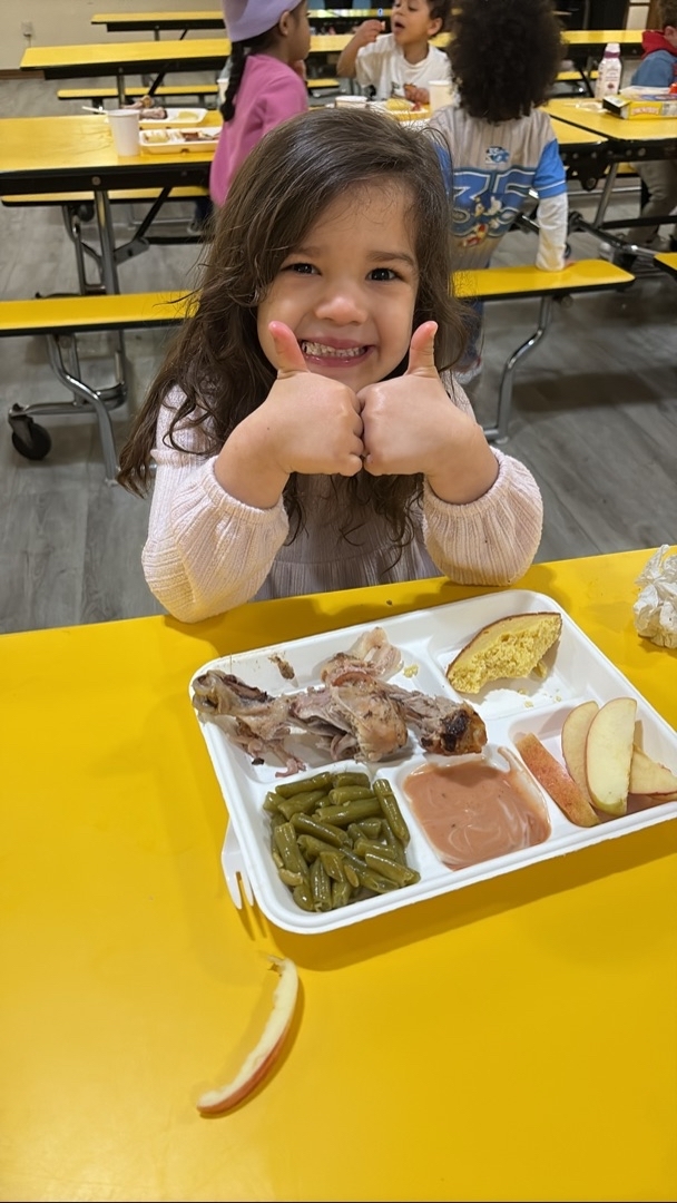 Child giving two thumbs up during a meal at Brookline Sprouts