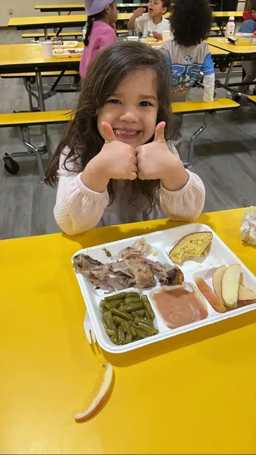 Child giving two thumbs up during a meal at Brookline Sprouts