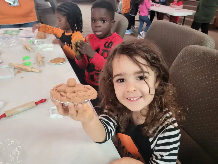 Preschool child proudly showing summer classroom work