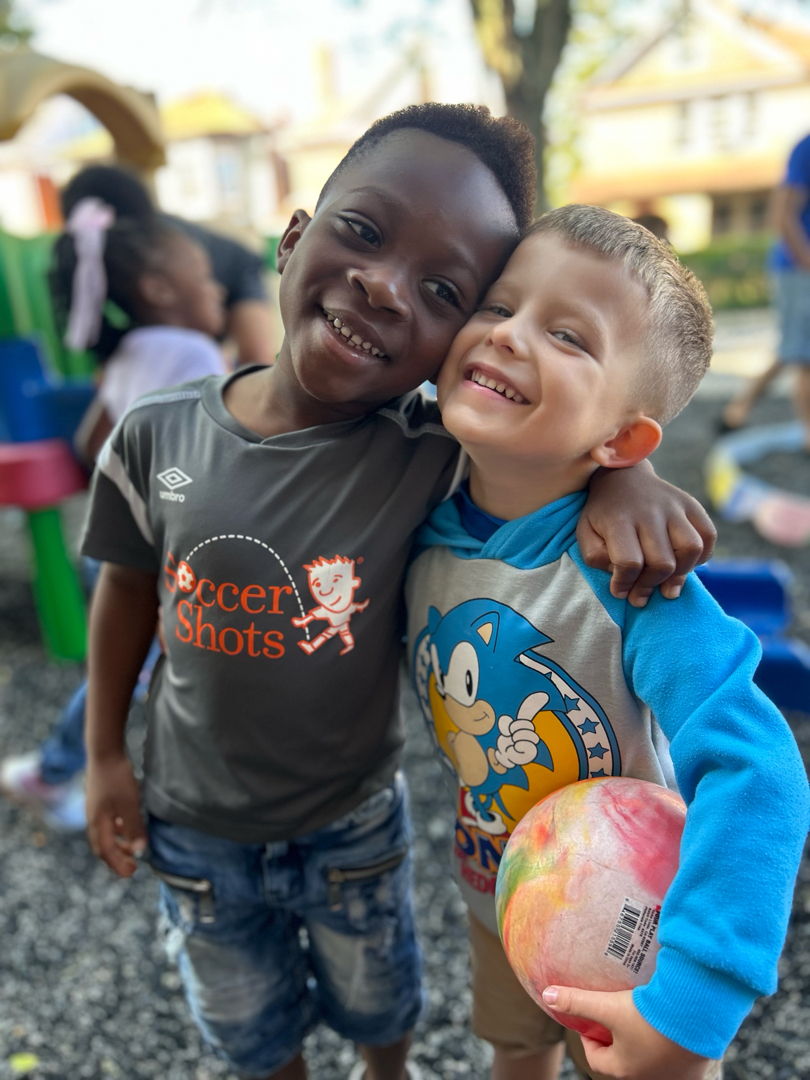 Two preschool children smiling together at Brookline Sprouts